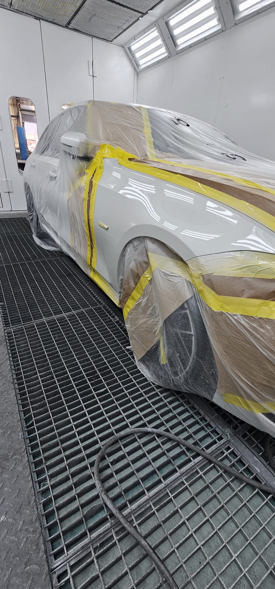 Painter spraying a car panel inside the workshop spray booth