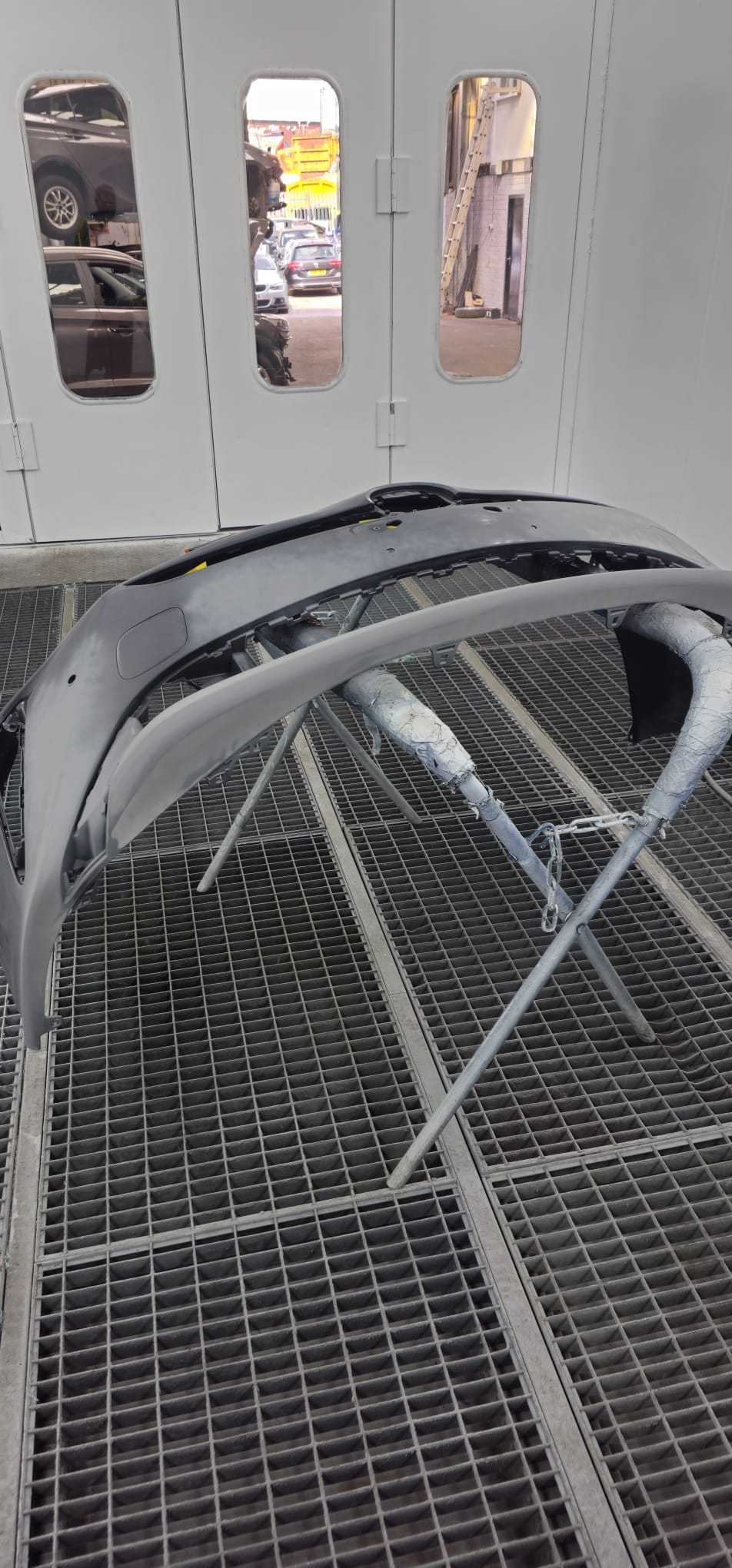 Car bumper on a stand being prepared and primed for paint